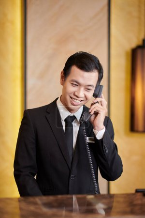 Téléchargez les photos : Portrait d'une réceptionniste souriante de l'hôtel répondant à un appel téléphonique - en image libre de droit