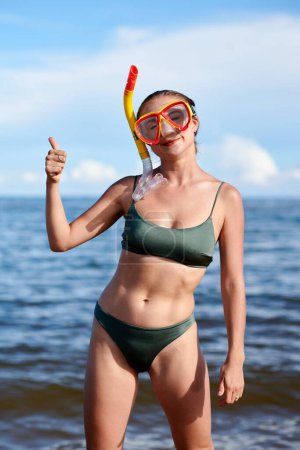 Foto de Retrato de mujer joven en forma excitada en traje de baño con máscara de snorkel y mostrando pulgares hacia arriba - Imagen libre de derechos