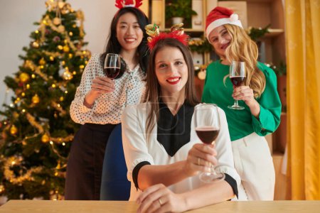 Photo for Joyful female entrepreneurs drinking wine when celebrating New Year in office - Royalty Free Image