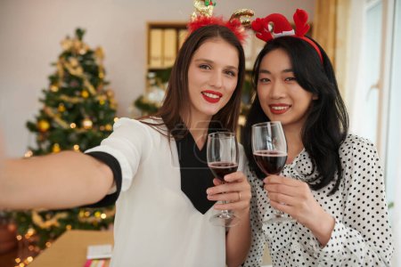 Téléchargez les photos : Souriant femmes entrepreneurs prendre selfie au bureau fête de Noël - en image libre de droit