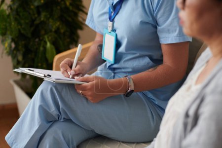 Foto de Imagen recortada del trabajador médico llenando el documento cuando visita al paciente en casa - Imagen libre de derechos