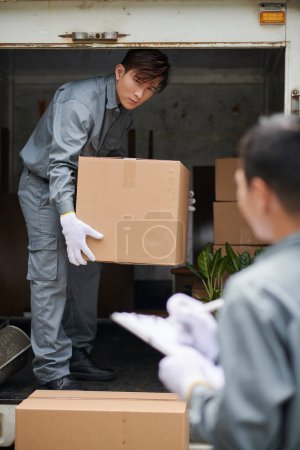 Photo for Mover loading boxes with belongings of client in van - Royalty Free Image