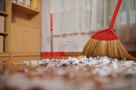 Photo for Janitor sweeping floor covered with ripped paper peaces - Royalty Free Image