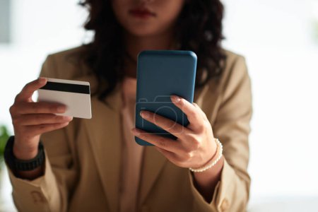 Foto de Primer plano de la mujer joven que utiliza la tarjeta de crédito para hacer compras en su teléfono inteligente - Imagen libre de derechos