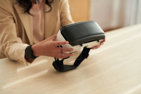 Photo for Close-up of young businesswoman using virtual reality glasses at her work while sitting at table - Royalty Free Image
