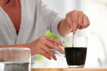 Foto de Primer plano de la mujer joven revolviendo azúcar en taza con café - Imagen libre de derechos