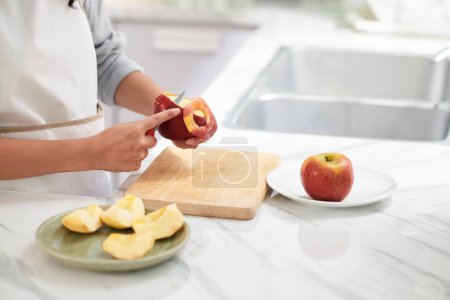 Téléchargez les photos : Gros plan d'une jeune femme coupant des pelures de pommes pour les manger pendant son alimentation - en image libre de droit