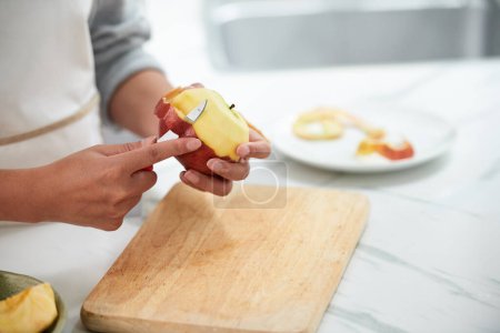 Foto de Primer plano de la joven mujer cortando la cáscara de la manzana madura para comerla - Imagen libre de derechos
