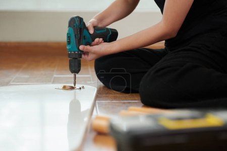 Foto de Primer plano de la mujer joven haciendo reparación con taladro en la habitación - Imagen libre de derechos