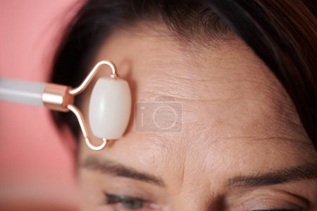 Photo for Closeup image of woman massaging forehead with roller to reduce appearance of wrinkles - Royalty Free Image