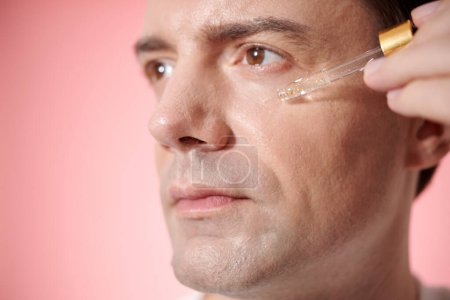 Foto de Hombre maduro aplicando suero de vitamina c en la cara para reducir las arrugas - Imagen libre de derechos
