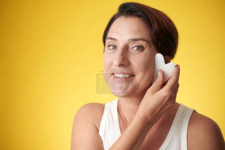 Photo for Face of happy mature woman doing massage with gua sha tool - Royalty Free Image