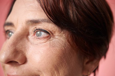 Foto de Imagen de cerca de una mujer madura con arrugas en los ojos mirando hacia otro lado - Imagen libre de derechos