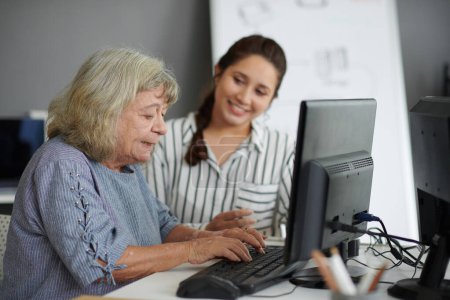 Téléchargez les photos : Femme âgée tapant sur l'ordinateur sous contrôle sur l'enseignant - en image libre de droit