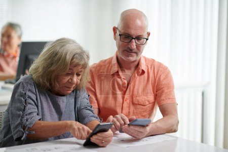 Téléchargez les photos : Personnes âgées apprenant à envoyer des messages texte et des photos sur les smartphones - en image libre de droit