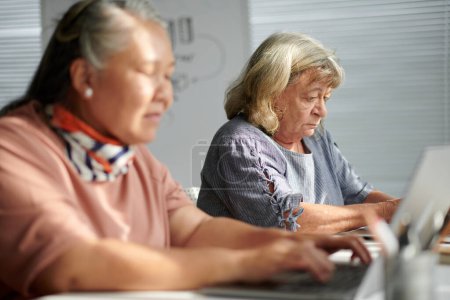 Téléchargez les photos : Femme âgée fréquentant un cours d'informatique pour acquérir des compétences de base - en image libre de droit
