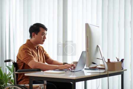 Photo for Young man with disability working as software developer at home - Royalty Free Image