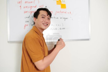 Photo for Portrait of cheerful developer standing at whiteboard with programming code - Royalty Free Image