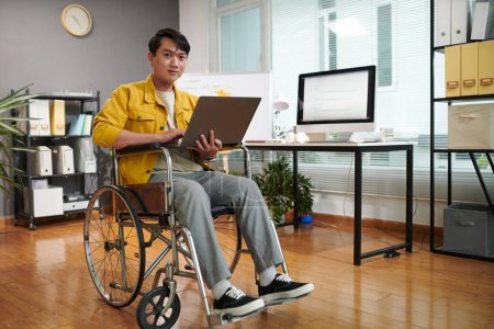 Téléchargez les photos : Jeune homme handicapé travaillant au démarrage dans son bureau - en image libre de droit