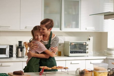 Photo for Happy girl hugging her mother who taught her how to bake Christmas cookies - Royalty Free Image