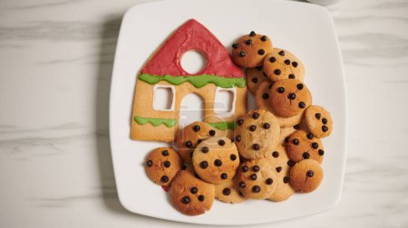 Foto de Placa con galletas caseras y casa de jengibre en el plato, vista desde arriba - Imagen libre de derechos