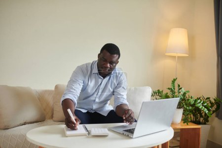 Photo for Serious entrepreneur working from home, checking e-mails and writing in planner - Royalty Free Image
