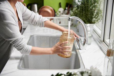 Photo for Cropped image of woman filling vase with tap water - Royalty Free Image