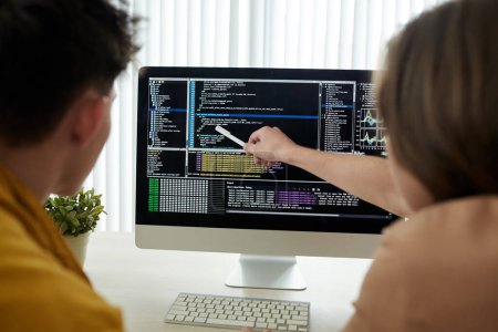 Foto de Jóvenes desarrolladores revisando el código de programación en la pantalla del ordenador - Imagen libre de derechos