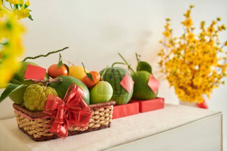 Foto de Cesta de frutas frescas de temporada decorada con lazo rojo preparado para el festival de primavera - Imagen libre de derechos
