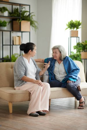 Foto de Mujer mayor contando chismes jugosos a su mejor amigo cuando la visita en casa - Imagen libre de derechos