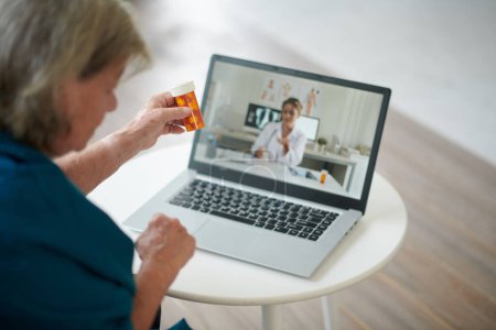 Foto de Mujer anciana que llama por video al médico para preguntarle con qué frecuencia debe tomar un medicamento nuevo - Imagen libre de derechos