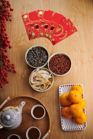 Photo for Lucky money red envelops on table next to sweet treats and teapot - Royalty Free Image