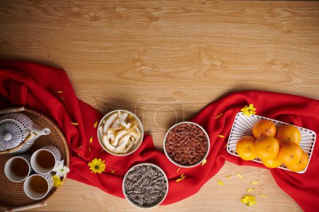 Téléchargez les photos : Bols avec des fruits confits et diverses graines à côté de théière sur la table décorée pour la célébration du Tet - en image libre de droit