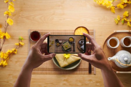 Téléchargez les photos : Mains de la personne photographiant des plats traditionnels vietnamiens cuits pour la célébration du Têt - en image libre de droit