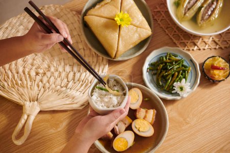Téléchargez les photos : Mains de la personne ayant du riz blanc avec haricots verts, porc braisé et gâteau carré pour le dîner de vacances - en image libre de droit