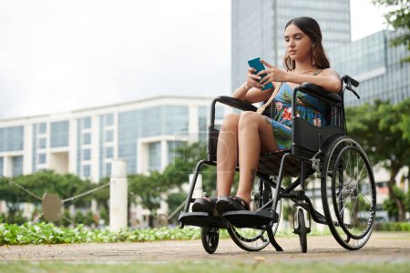 Foto de Mujer joven con discapacidad respondiendo mensajes de texto de amigos - Imagen libre de derechos