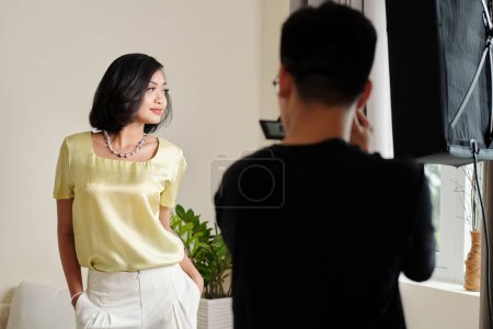 Téléchargez les photos : Modèle de mode asiatique posant pour photographe pendant le tournage professionnel - en image libre de droit