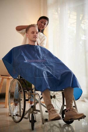 Téléchargez les photos : Coiffeur est rentré chez l'homme handicapé pour se couper les cheveux - en image libre de droit