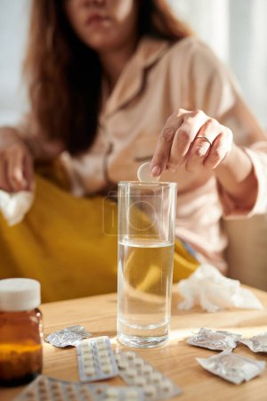 Foto de Imagen recortada de la mujer poniendo tableta de aspirina en un vaso de agua - Imagen libre de derechos