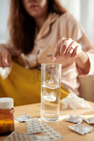 Foto de Mujer enferma disolviendo tableta de aspirina en un vaso de agua - Imagen libre de derechos