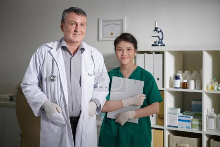 Photo for Smiling experienced veterinarian and medical nurse standing in clinic - Royalty Free Image