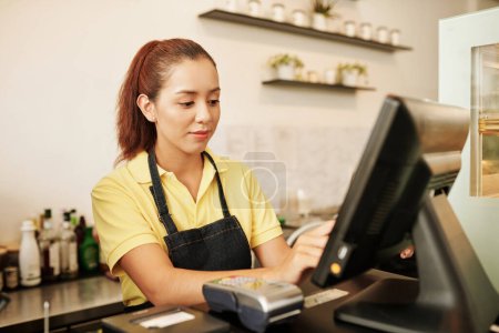 Photo for Smiling female cafe waitress working at cashier desk - Royalty Free Image