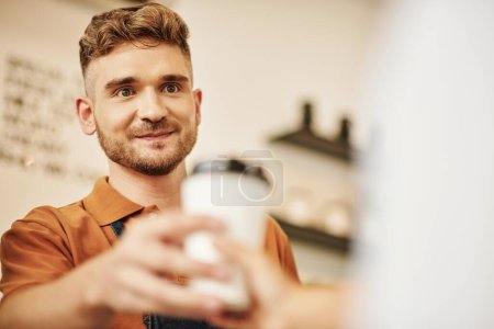 Téléchargez les photos : Portrait de barista de café souriant donnant une tasse de café au client - en image libre de droit