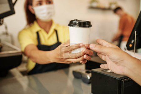 Photo for Close-up image of female coffeeshop barista giving cup of coffee to customer - Royalty Free Image