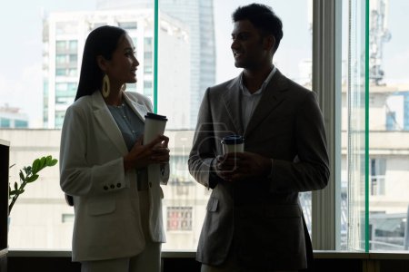 Téléchargez les photos : Silhouettes de gens d'affaires buvant du café contre une grande fenêtre de bureau - en image libre de droit