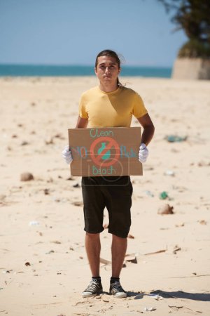 Téléchargez les photos : Jeune homme sérieux demandant aux gens de ne pas laisser de plastique sur la plage - en image libre de droit