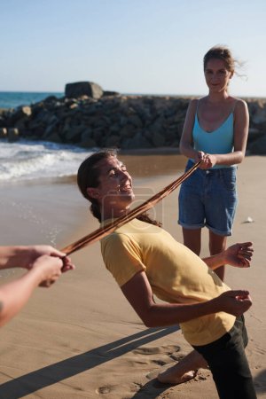 Foto de Grupo de amigos felices jugando al limbo en la playa cuando disfrutan de la fiesta de cumpleaños - Imagen libre de derechos