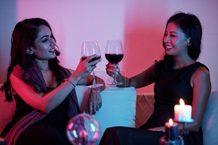 Téléchargez les photos : Des amies souriantes buvant du vin après s'être dit bonne fortune - en image libre de droit