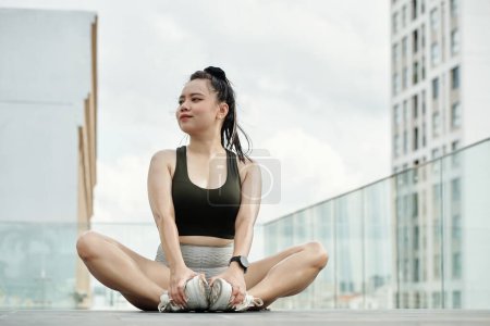 Photo for Smiling fit young woman working out on building rooftop in the morning - Royalty Free Image