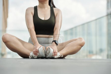 Téléchargez les photos : Image recadrée d'une sportive faisant de l'exercice d'étirement pour les jambes - en image libre de droit